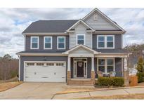 Charming two-story home featuring a two-car garage, inviting front porch with seating and beautiful grey siding at 1204 Castlestone Ln, Knightdale, NC 27545
