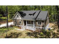 Inviting exterior view of home with covered porch, attractive siding, and beautifully landscaped yard surrounded by mature trees at 149 Amber Rd, Timberlake, NC 27583