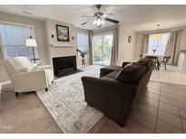 Bright living room featuring a fireplace, ceiling fan, sliding glass doors, and a neutral color palette at 1613 Bulon Dr, Cary, NC 27518