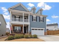 Charming two-story home features a welcoming front porch, a two-car garage, and classic blue siding at 204 Cassada Ct, Holly Springs, NC 27540
