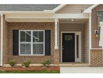 Charming brick home entrance featuring a black front door, large window, and well-maintained landscaping at 210 Cason Dr, Gibsonville, NC 27249