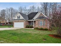 Charming brick home with a manicured lawn, attached garage, and flowering tree at 2241 Rock Bridge Dr, Mebane, NC 27302