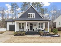 Charming two-story home featuring a welcoming front porch with seating and manicured landscaping at 228 Sacred Fire Rd, Louisburg, NC 27549