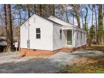 Charming bungalow-style home with white siding and a brick foundation in a wooded neighborhood at 2506 Dominion St, Durham, NC 27704