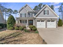 Charming two-story home featuring a well-manicured lawn, stone accents, and a welcoming front porch at 2912 Oakley Woods Ln, Apex, NC 27539