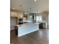 Bright, modern kitchen featuring a large island, stainless steel appliances, and stylish pendant lighting at 321 Kavanaugh Rd, Wake Forest, NC 27587