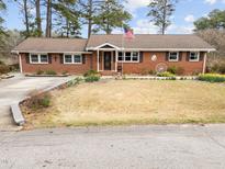 Charming brick home with an American flag displayed and a well-maintained front yard with blooming flowers at 412 N Cheatham St, Franklinton, NC 27525