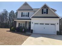 Two-story home with a two car garage, neutral siding and black shutters, landscaping, and a blue sky at 433 Falling Brook Dr, Kenly, NC 27542