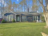 Charming blue home featuring a well-manicured lawn and inviting front porch with chairs at 6312 Cape Charles Dr, Raleigh, NC 27617