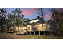 Exterior view showcasing a wooden deck with railing and gray siding and a view of the sunset in the background at 75 Traceway N, Sanford, NC 27332