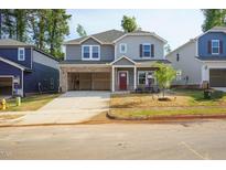 Two-story home with gray siding, brick accents, an attached garage, and a landscaped front yard at 157 Klamath Dr, Garner, NC 27529