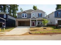 Two-story home features gray siding, brick accents, open garage and newly sodded yard at 157 Klamath Dr, Garner, NC 27529