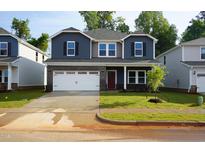 Charming two-story home featuring a two-car garage, brick accents, and a well-manicured front lawn at 165 Klamath Dr, Garner, NC 27529