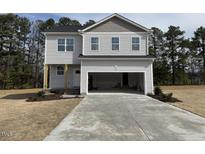 Two-story home with gray siding, an attached garage, and a well-manicured lawn at 20 Diamond Creek Dr, Zebulon, NC 27597