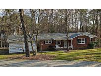 Cozy red brick ranch-style home with a gray roof and front porch swing nestled among trees at 209 High House Rd, Cary, NC 27513