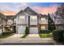 Charming townhome with a two-car garage and stone and siding exterior, set against a colorful sunset sky at 2302 Wispy Green Ln, Raleigh, NC 27614