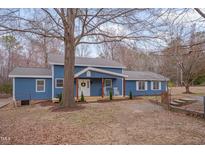 Charming blue home featuring a welcoming front porch with rocking chairs, set amidst a serene landscape at 2403 June Dr, Hillsborough, NC 27278