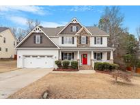 Inviting two-story home with a charming front porch, a red door and manicured landscaping at 244 Winding Oak Way, Clayton, NC 27520