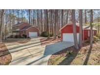 View of the home's exterior with an attached garage and a detached garage, both with large driveways at 2501 Huntsman Trl, Zebulon, NC 27597