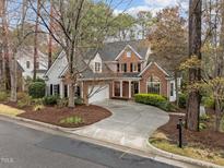 Charming brick two-story home with black shutters, a manicured lawn, and a curved driveway at 2504 Wertherson Ln, Raleigh, NC 27613