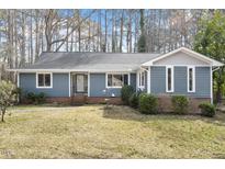 Charming blue single-story home with a well-manicured front yard and mature trees, offering a serene setting at 3816 Saratoga Dr, Raleigh, NC 27604