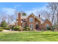 Stunning brick home boasts large windows, detailed trim, lush landscaping, and a manicured lawn under a bright, blue sky at 4405 Turnberry Cir, Durham, NC 27712