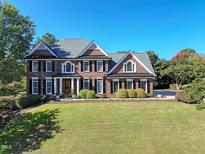 Charming brick home with manicured lawn, mature trees, and classic architectural details at 704 Walcott Way, Cary, NC 27519