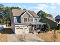 Charming two-story home featuring stone accents, a covered porch, and a two-car garage at 253 Bendemeer Ln, Rolesville, NC 27571