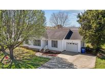 Charming single-story home with white siding, a garage, and a well-maintained front yard with mature trees at 309 Old Farm Dr, Graham, NC 27253