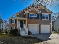 Charming two-story home featuring a brick facade, two-car garage, and a welcoming entrance with blue shutters at 3413 Asgar Ct, Raleigh, NC 27610