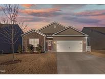 Charming single-Gathering home featuring stone accents, a two-car garage, and a well-maintained lawn under a colorful sky at 358 E Painted Way Way, Clayton, NC 27527