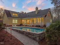 Beautiful backyard features a well-maintained rectangular pool, stone patio, and sprawling lawn at 5301 Crocus Ct, Holly Springs, NC 27540