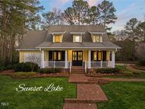 Charming yellow home with a welcoming front porch, lush landscaping, and a brick walkway at 5301 Crocus Ct, Holly Springs, NC 27540