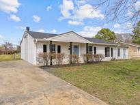 Charming single-story home with white brick, black shutters, and a blue front door, complete with a manicured lawn at 711 Wheat Mill Rd, Durham, NC 27704