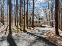 Charming two-story home with yellow siding, mature trees, and a long driveway in a wooded setting at 8111 Reynard Rd, Chapel Hill, NC 27516