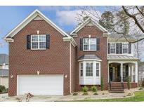 Charming two-story brick home featuring a manicured lawn, front-facing garage, and inviting front porch at 8417 Dunnington Cir, Raleigh, NC 27613