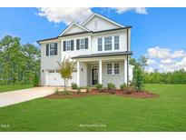Beautiful two-story home featuring a well-manicured lawn and classic architecture with a gray brick facade at 8729 Maxine St # 38, Willow Springs, NC 27592