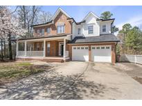 Stately two-story home with a brick facade, inviting front porch, and a spacious three-car garage at 101 Palmwood Ct, Cary, NC 27519