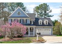 Charming two-story home with blue siding, a two-car garage, and blooming tree in the front yard at 104 Stenness Ct, Apex, NC 27502