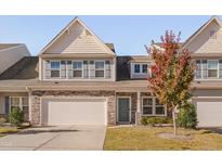 Charming townhome with stone accents, attached garage, manicured lawn, and a pop of color from the front tree at 106 Florence Pl, Morrisville, NC 27560