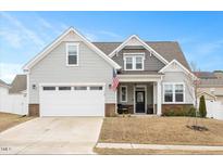 Charming two-story home with a two car garage, American flag, and a well-maintained lawn at 108 Wise Oak Ln, Garner, NC 27529