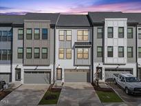 Charming townhome showcases a contemporary design with a two-car garage, and a gray and white color scheme at 1207 Corkery Ridge Ct, Cary, NC 27519