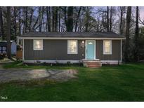 Charming single-story home featuring a light-blue front door, well-manicured lawn, and mature trees at 1208 Goldsboro Ave, Sanford, NC 27330