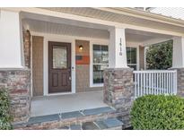 Inviting front porch with stone accents, columns, and American flag decoration at 1416 Endgame Ct, Wake Forest, NC 27587