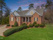 Charming brick home with a manicured lawn and inviting front porch, perfect for relaxation at 3204 Cobblestone Ct, Raleigh, NC 27607