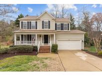 Charming two-story home featuring a welcoming front porch, attached two-car garage, and manicured landscaping at 733 Hillsford Ln, Apex, NC 27502