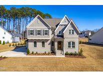 Charming two-story home boasts a blend of brick and gray siding, complemented by a manicured lawn and bright blue sky at 8132 Baronleigh Ln, Wake Forest, NC 27587