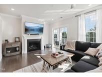 Bright living room featuring a fireplace, mounted television, and sliding door access to a small balcony at 10320 Sablewood Dr # 107, Raleigh, NC 27617