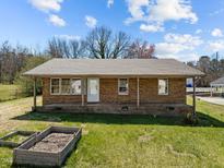 Charming single-story brick home with a covered front porch, surrounded by a lush green lawn at 107 Rencher St, Hillsborough, NC 27278