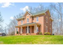 Charming red brick two-story home with a green roof and inviting wrap-around porch at 1100 Reatkin Ln, Graham, NC 27253